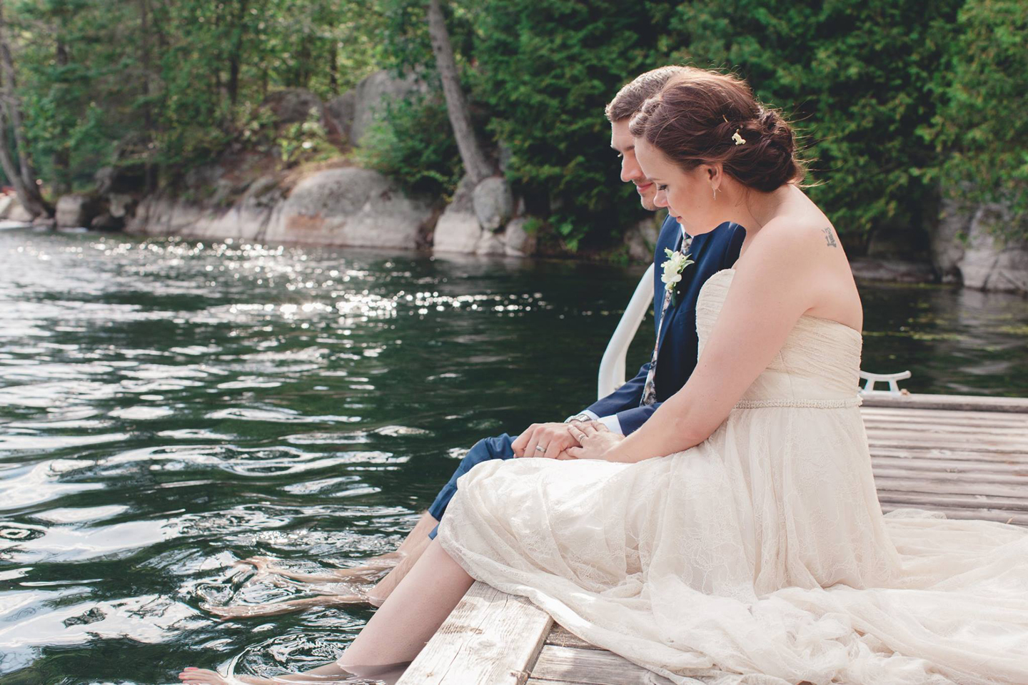 bride and groom sitting on the dock after wedding